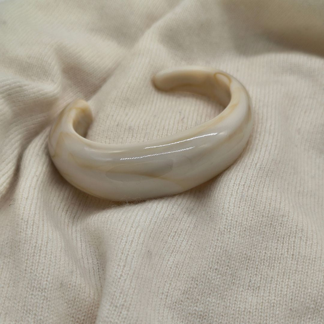Deze prachtige offwhite gemarmerde bangle in organische vorm is gemaakt van acryl. Tijdelijk verkrijgbaar bij Gioia.
