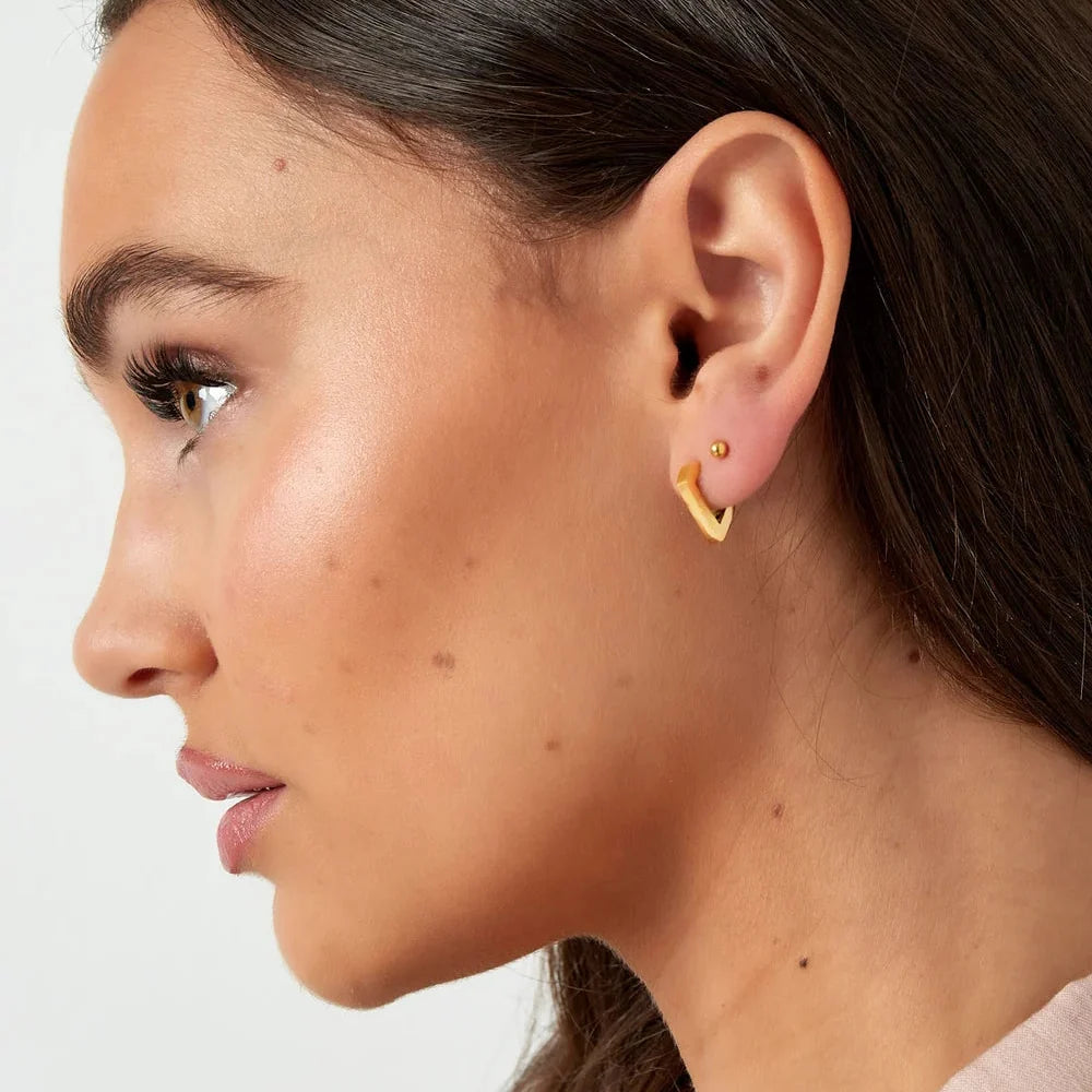 Een vrouw van side profile die het diamant oorbelletje laat zien. Minimalistische RVS oorbellen goudkleur, voor de moderne vrouw.