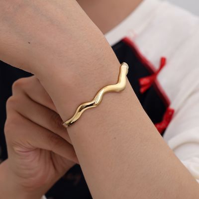 Wave bangle goudkleurig RVS. Moderne en organische sieraden.