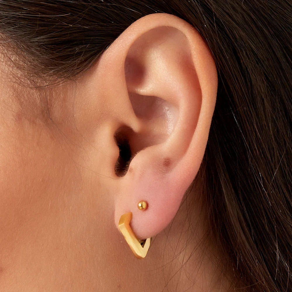 Een vrouw van side profile die het diamant oorbelletje laat zien. Minimalistische RVS oorbellen goudkleur, voor de moderne vrouw.