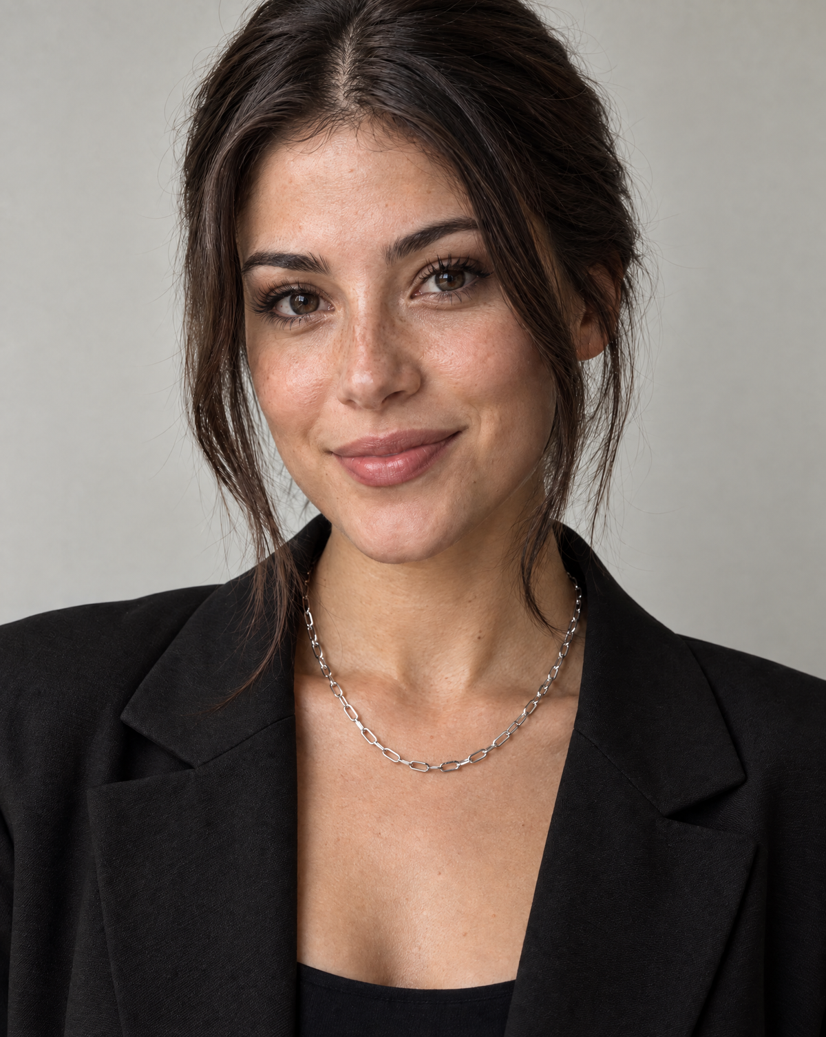 Vrouw draagt de Luna Chain zilverkleurige RVS schakelketting met langwerpige schakels en een zwarte blazer.