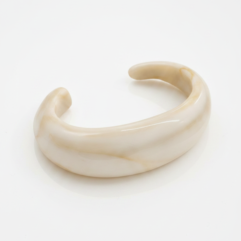 Soft Stone Bangle – witte achtergrond

The soft stond bangle in offwhite met een beige marmering erin. Het design is een open bangle dit dikker is in het midden en taps toeloopt richting de einden. Gemaakt van hars, dus lichtgewicht en comfortabel